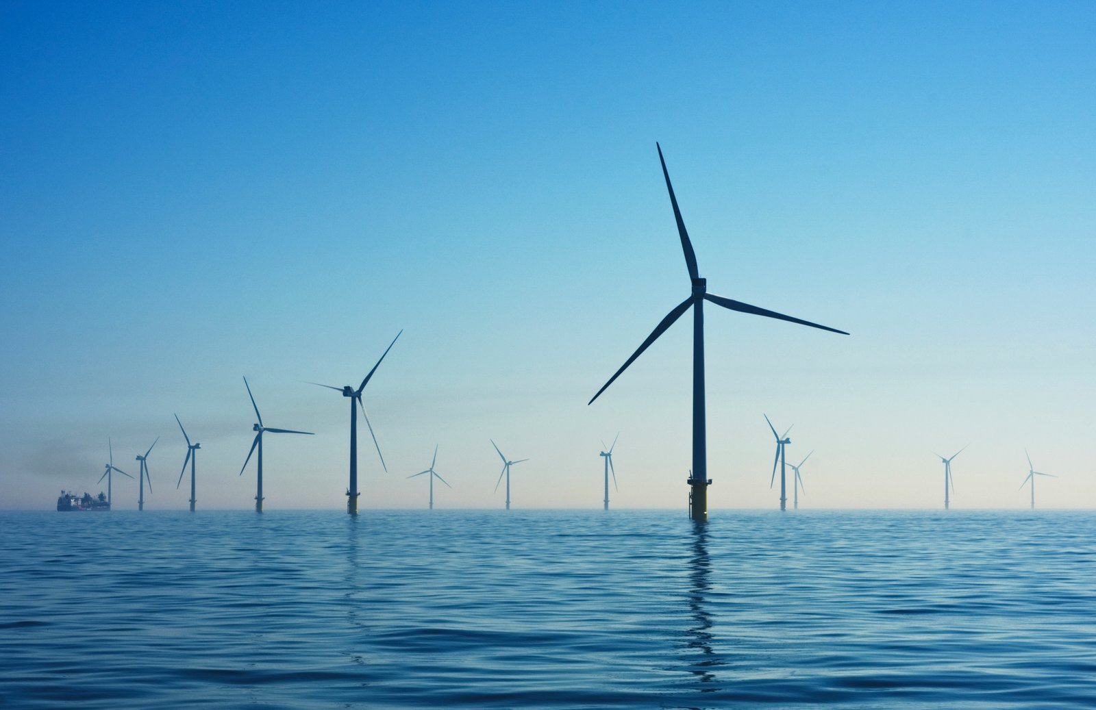 Windmills in the foreground and in the distance are part of an offshore windfarm.